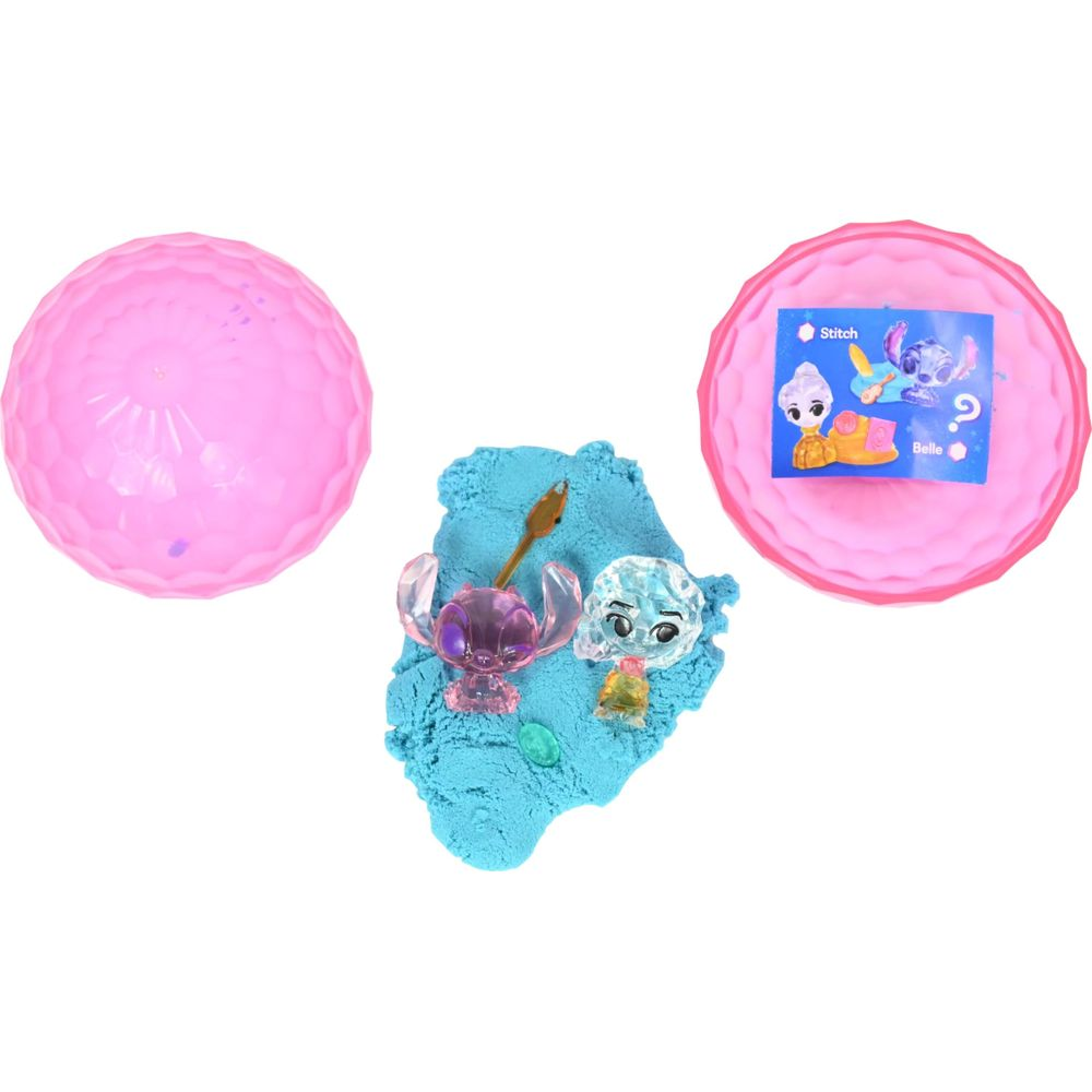 Deux figurines Stitch, une rose et une bleue, sur du sable bleu à côté d'une sphère rose.