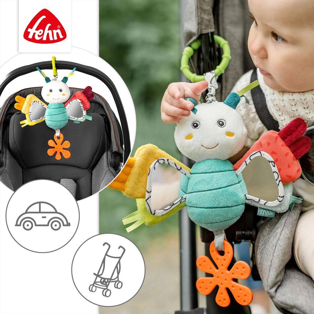 Un bébé joue avec un hochet papillon en peluche attaché à une poussette.