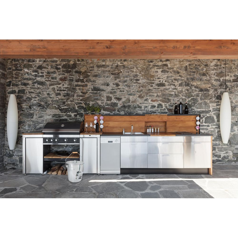Una cucina da esterno con grill, lavastoviglie, lavello e armadi di fronte a un muro di pietra.