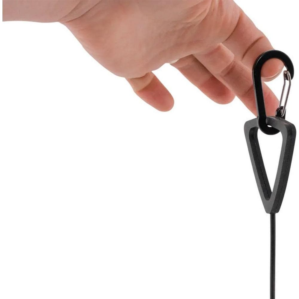 Une main tient un mousqueton noir avec un pendentif triangulaire.
