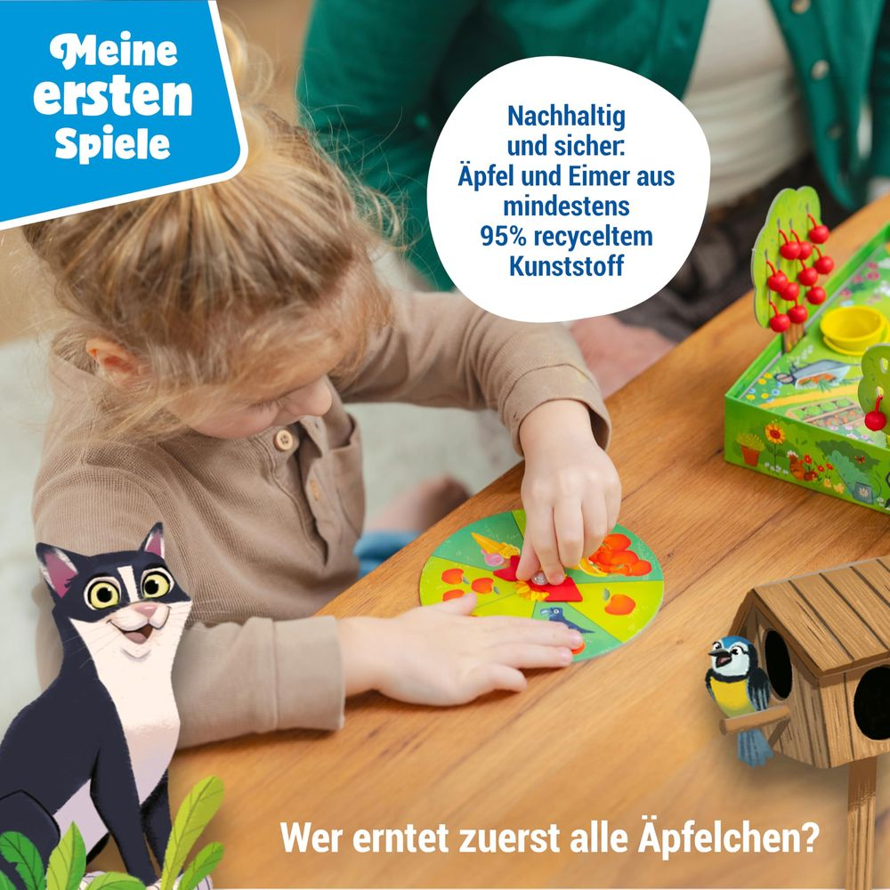 Ein Kind spielt ein Apfel-Ernte-Spiel mit Spielzeug. Eine Katze und ein Vogel sind zu sehen.