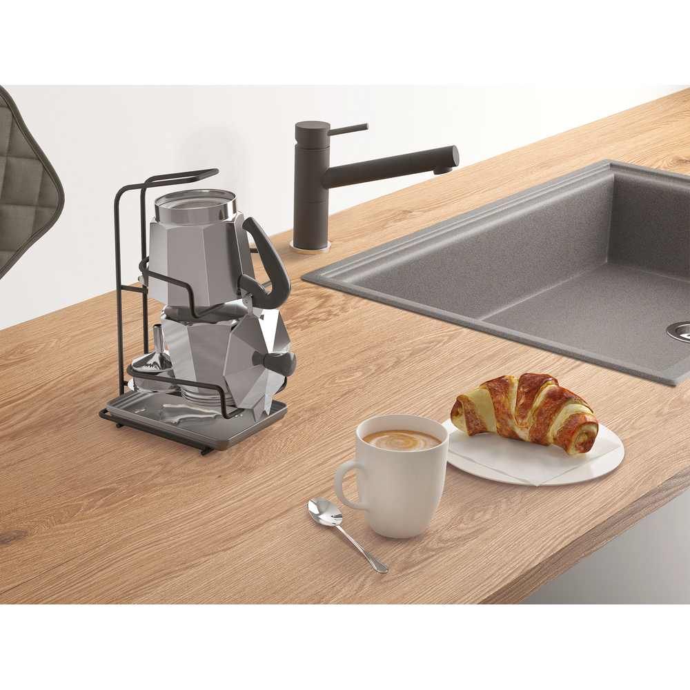 Kaffeemaschine, Tasse Kaffee, Croissant und Spüle auf Holzarbeitsplatte.