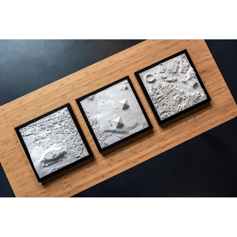 Trois maquettes de villes blanches avec bâtiments, pyramides et un Colisée.