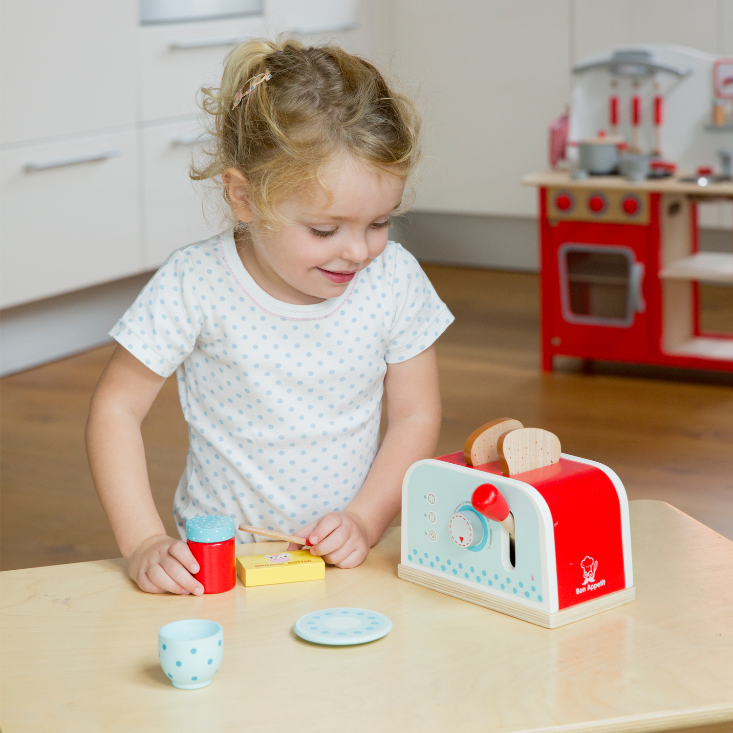 Una bambina gioca con un tostapane giocattolo e altri oggetti da cucina.