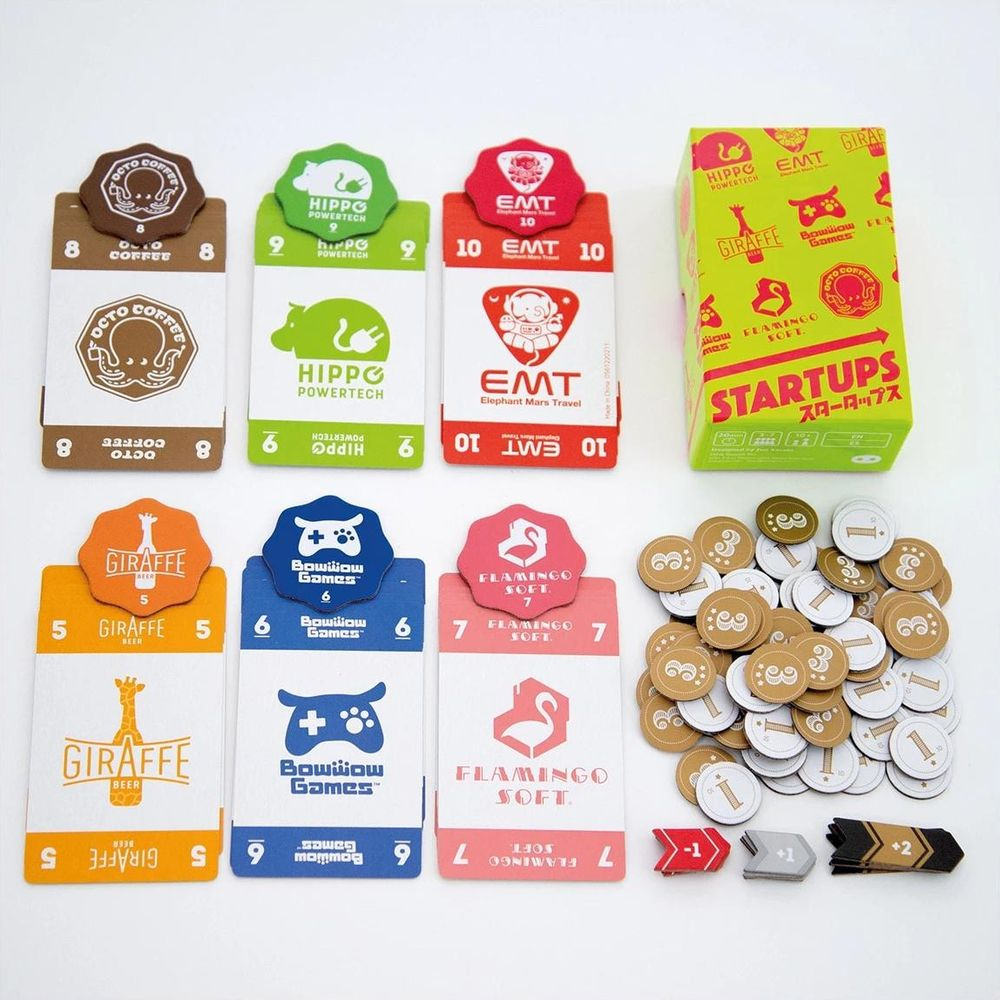 Brettspielkomponenten: Karten mit Tieren, Münzen, Spielbox mit „Startups“.