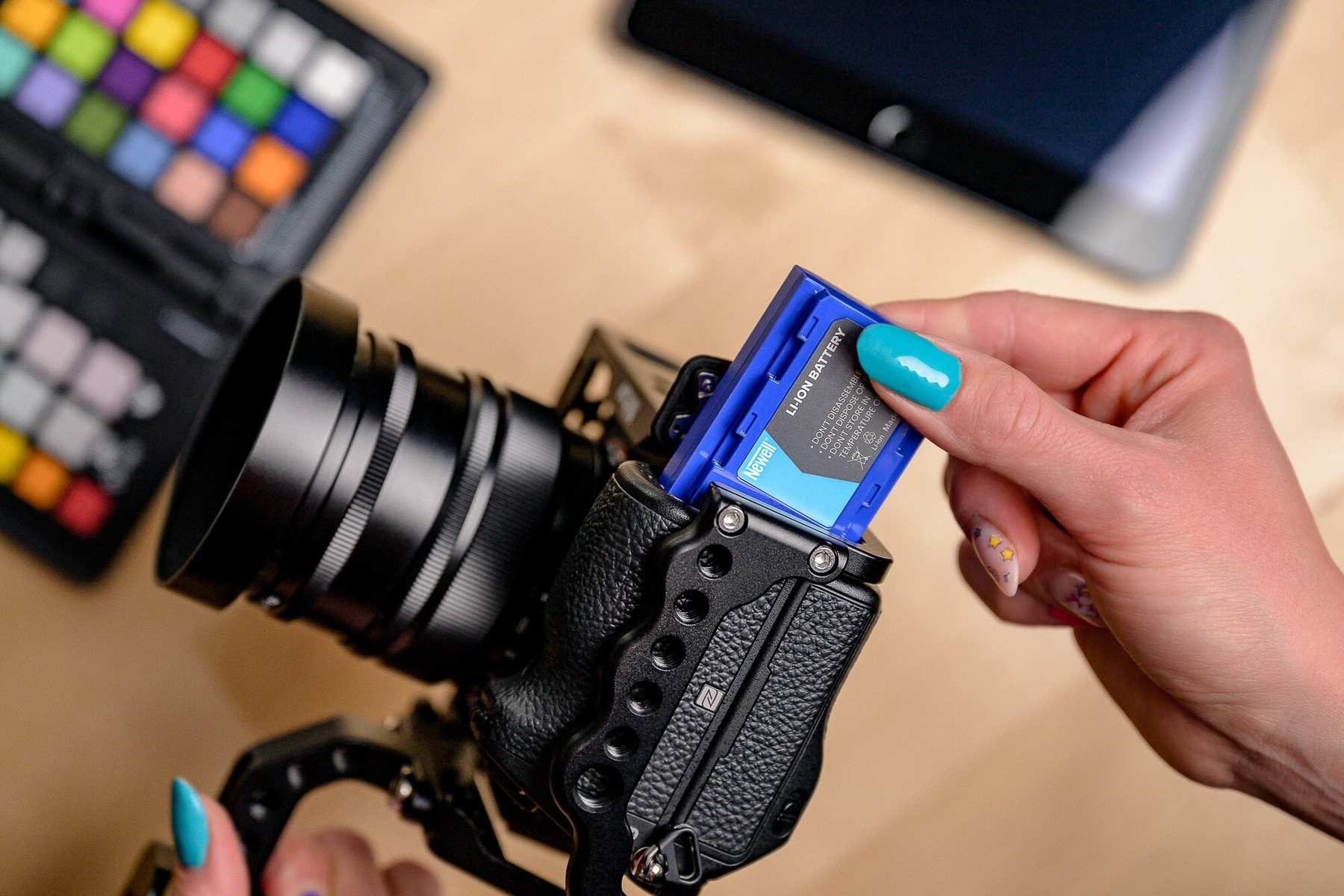 Eine Hand setzt eine blaue Li-Ion-Batterie in eine Kamera ein.