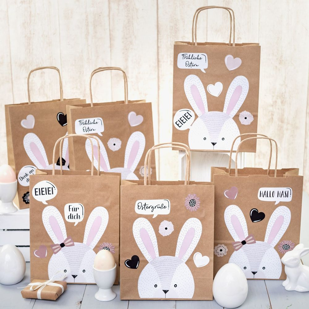 Sacchetti di carta marroni di Pasqua decorati con coniglietti e testo come 'Buona Pasqua'.