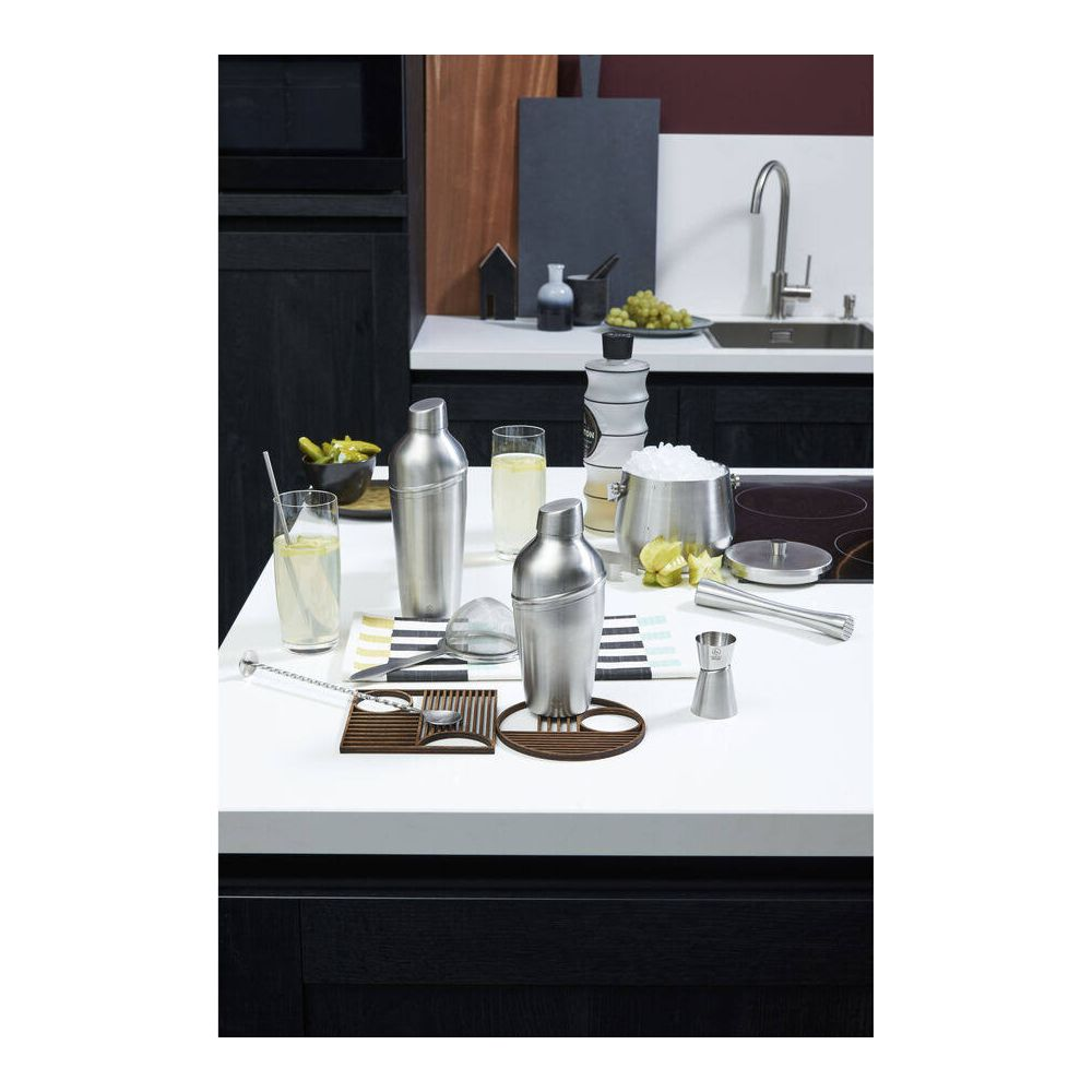 Ein Bartisch mit Cocktailzubehör: Shaker, Gläser, Eisbehälter und Garnituren.
