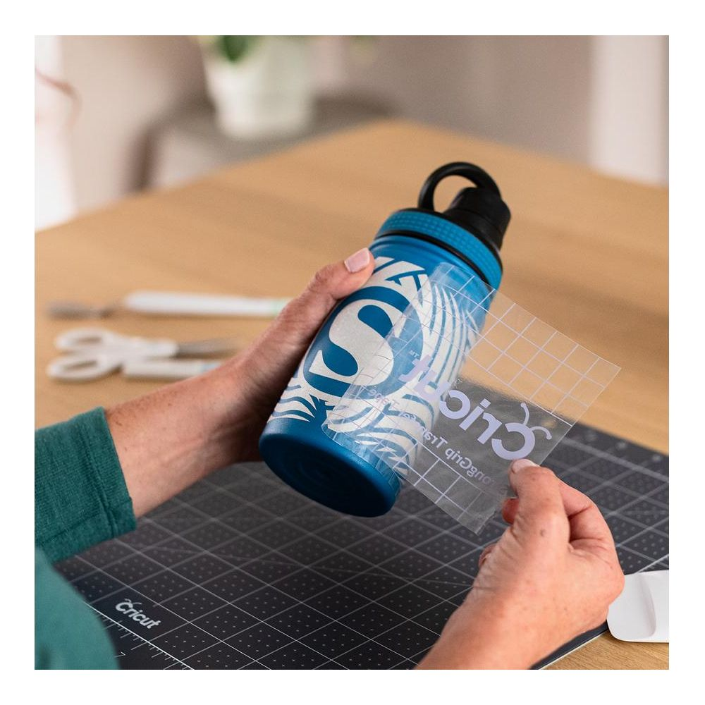 Eine Person bringt eine Aufkleber-S-Initialen auf eine blaue Wasserflasche an.