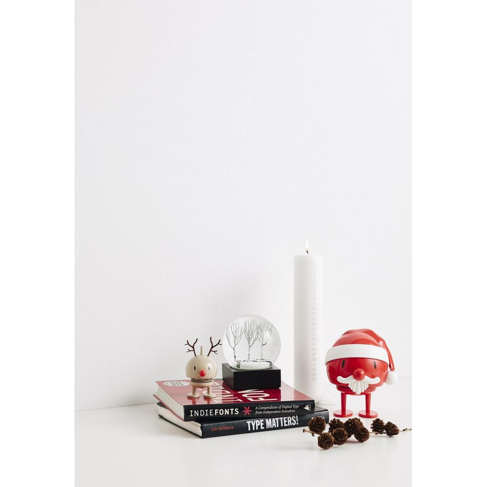 Un giocattolo renna, globo di neve, due libri, candela e giocattolo Babbo Natale.