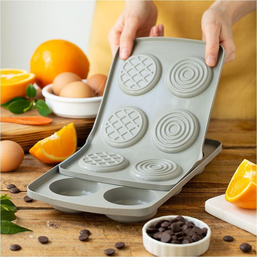 Graue Silikonform für Kuchen mit Orangen, Eiern und Schokoladenstückchen.