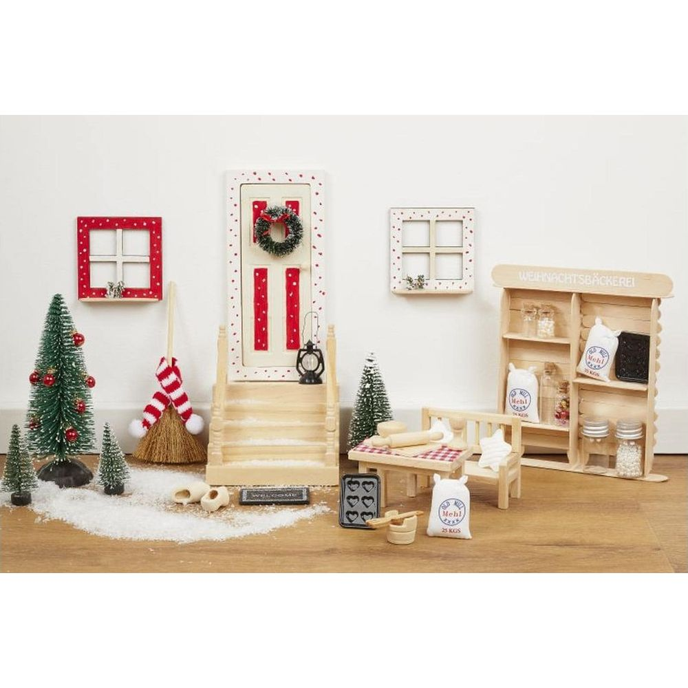 Miniatur-Weihnachtsbäckerei mit Tür, Fenstern, Bäumen und Möbeln.