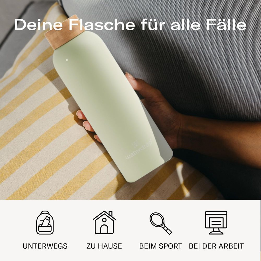 Helle grüne Wasserflasche mit Holzdeckel, gehalten von einer Hand.