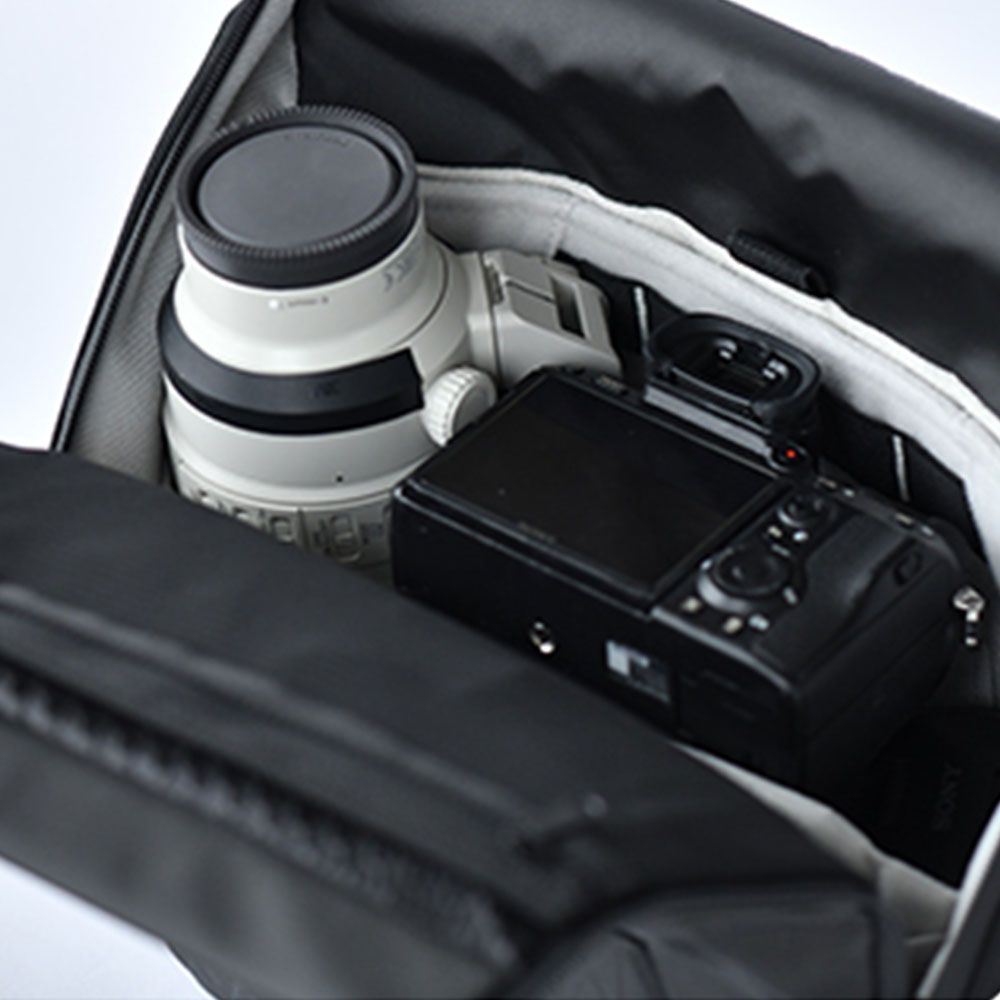 Una fotocamera bianca con obiettivo riposa in una borsa nera.