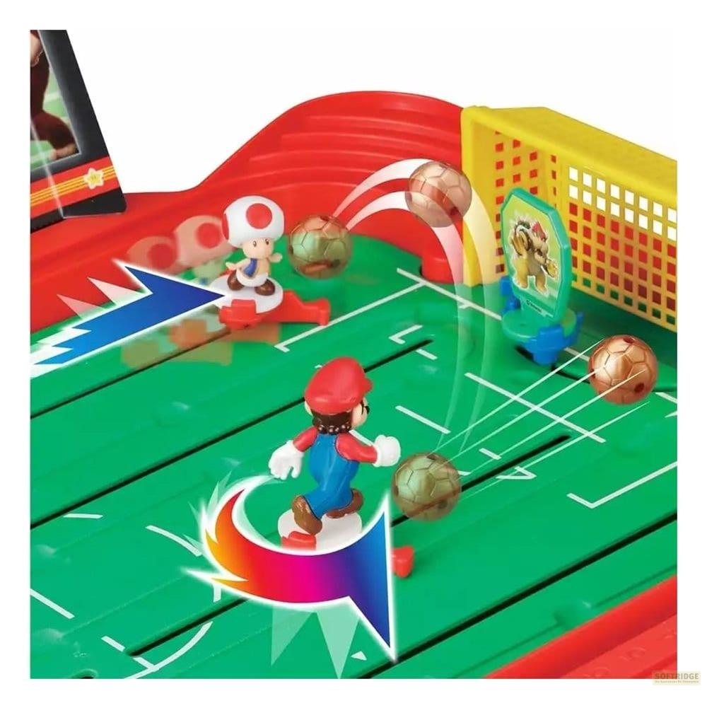 Figure di Mario e Toad giocano a calcio su un campo verde con porta gialla e barriere rosse.