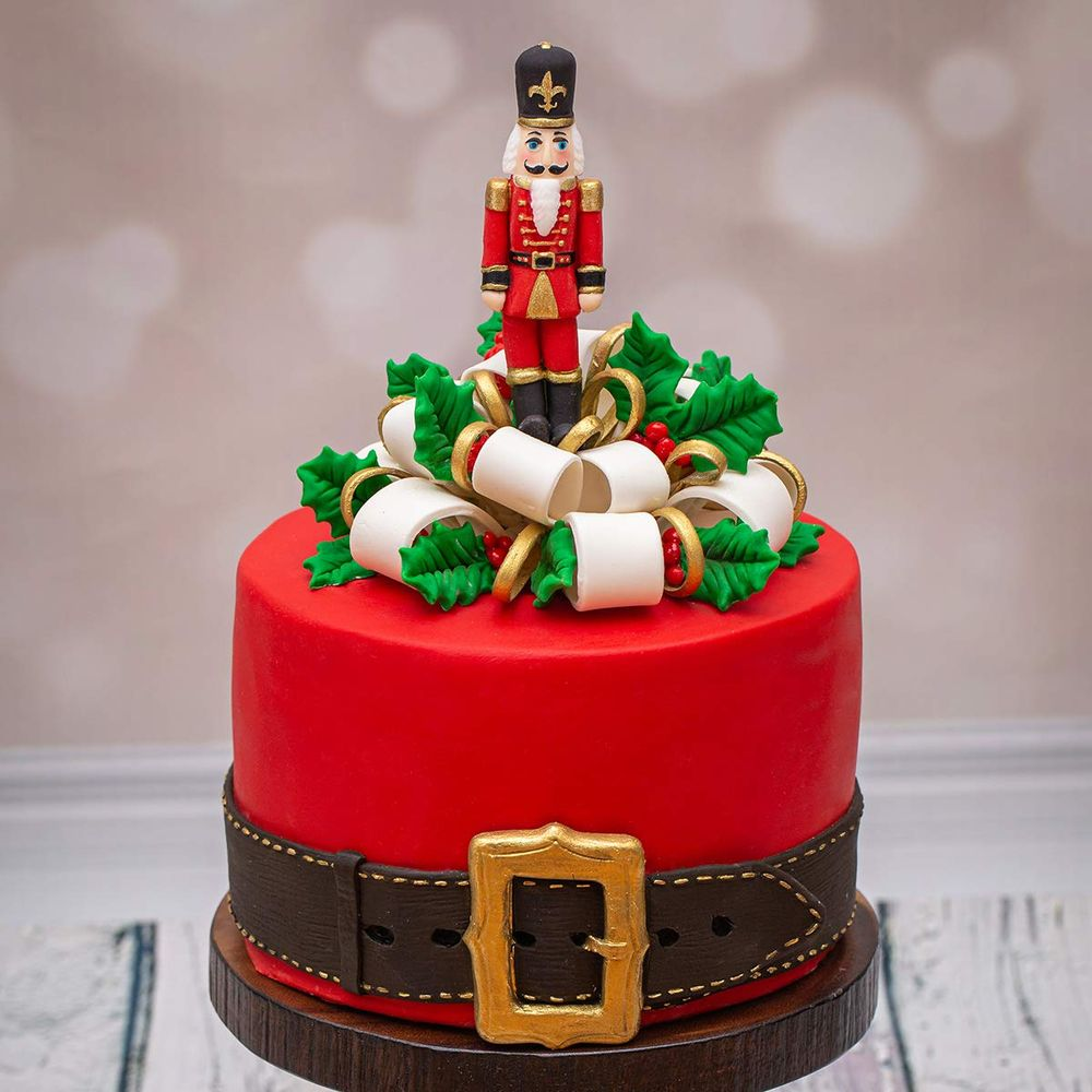 Rote Torte mit Nikolausgürtel, Nussknacker, Stechpalme und Band.