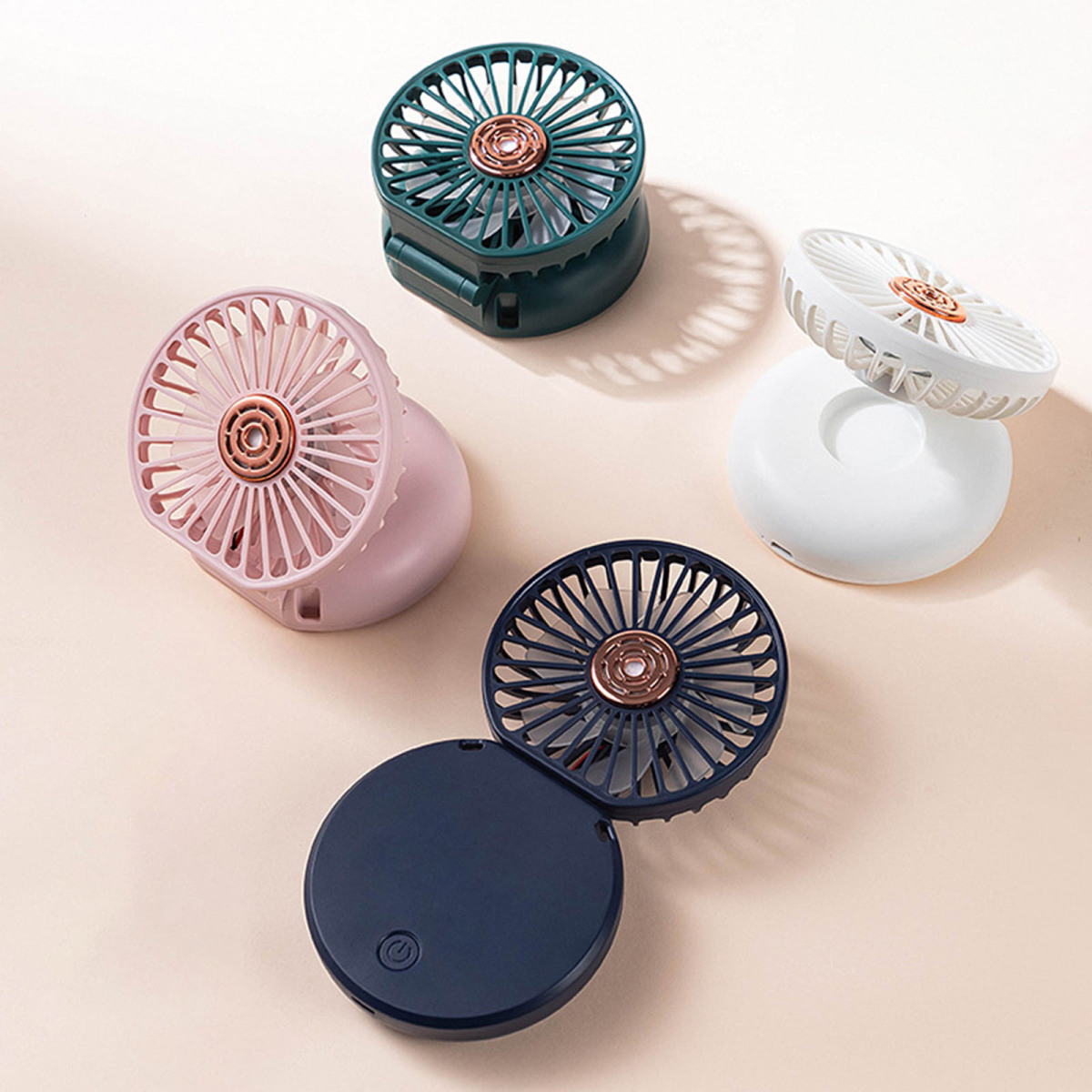 Fünf tragbare Mini-Ventilatoren in Rosa, Dunkelgrün, Weiß und Dunkelblau.