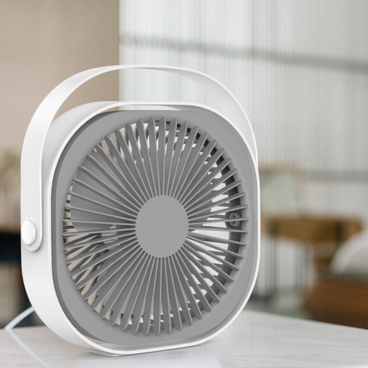 Ein weißer tragbarer Ventilator mit grauem Gitter auf einem Tisch.