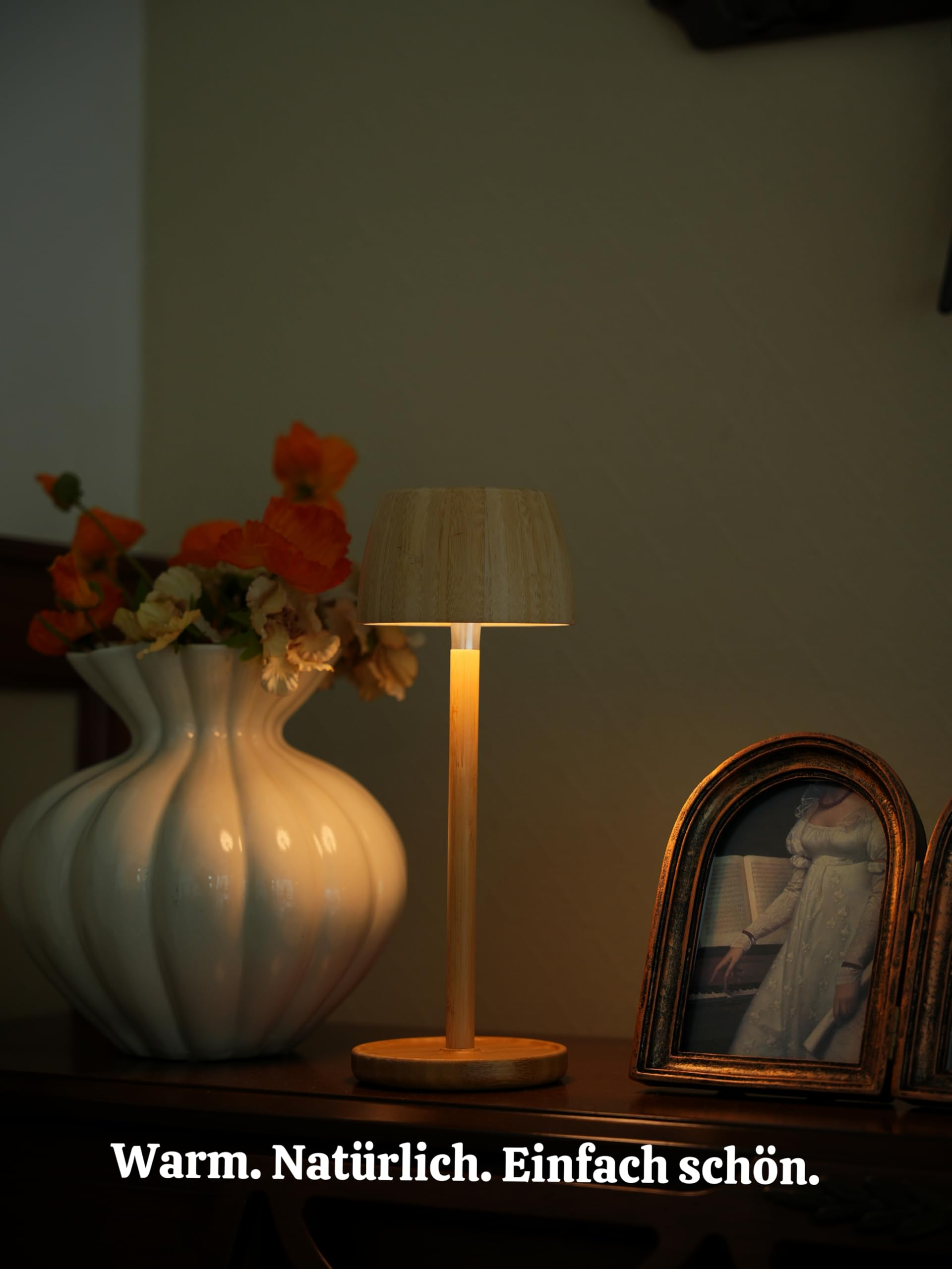 Ein Nachttisch mit einer Lampe, Vase und zwei Bilderrahmen. Warmes Licht.