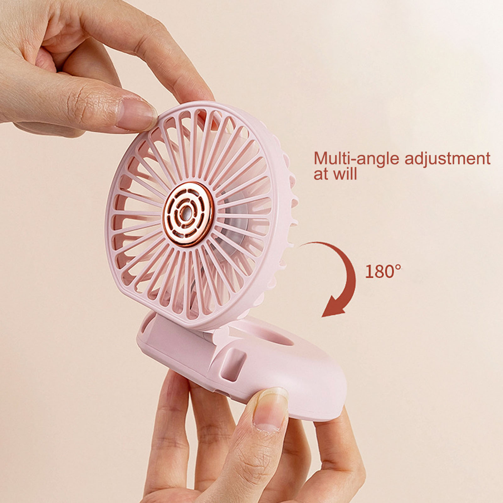Eine Hand hält einen kleinen, rosafarbenen Ventilator, der um 180 Grad verstellbar ist.
