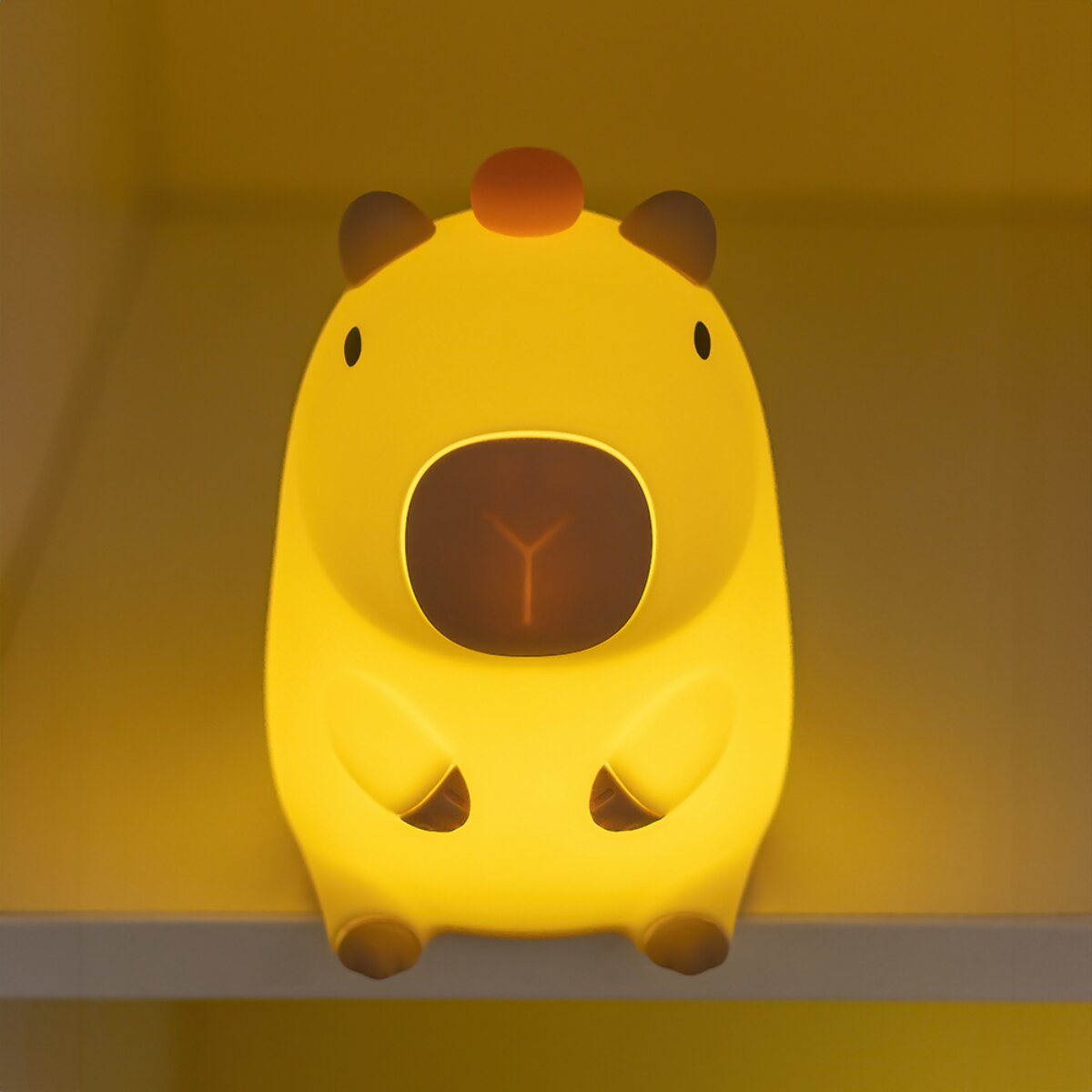Eine gelbe Capybara-Lampe mit einem orangen Punkt auf dem Kopf.