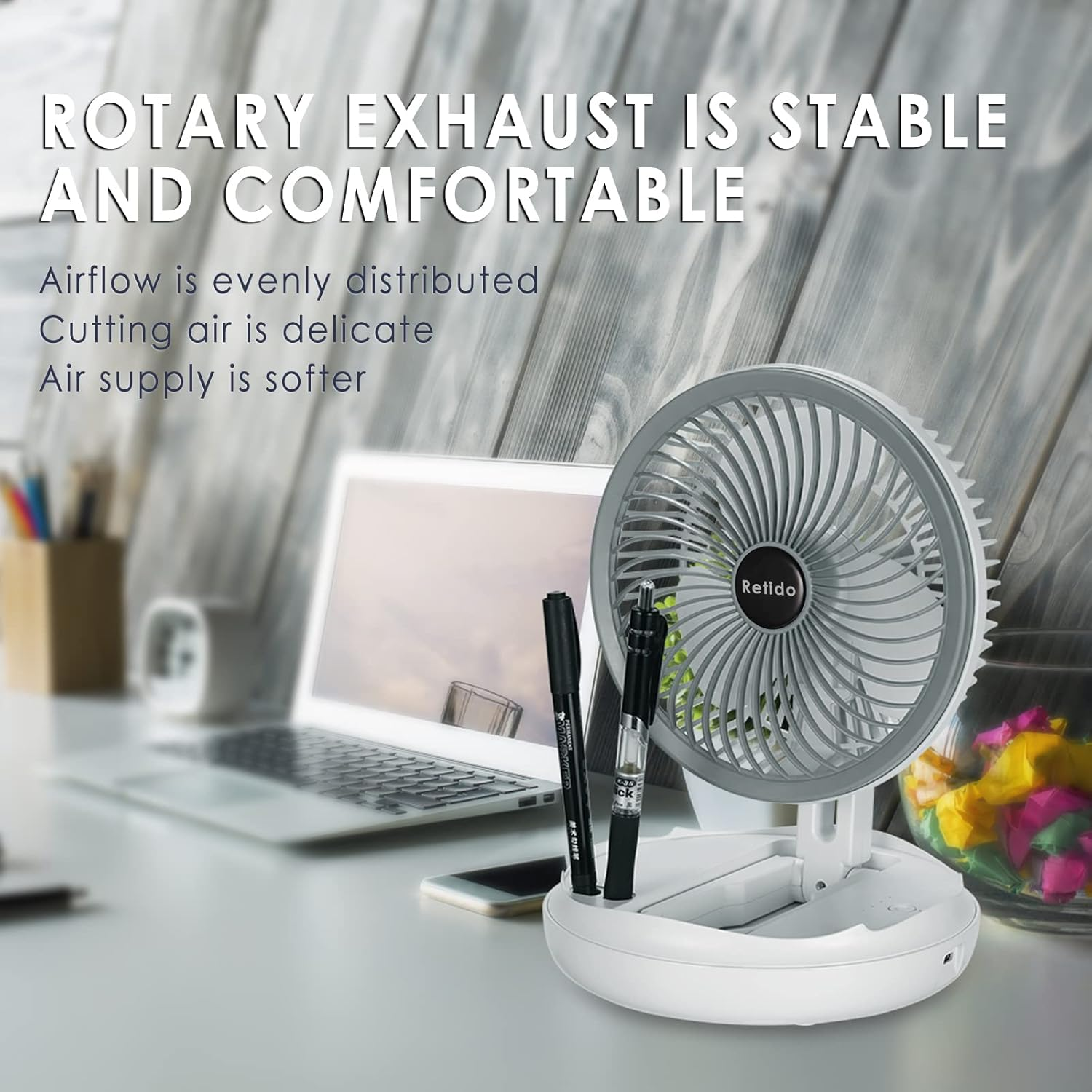 Ein weißer Ventilator mit zwei Stiften steht auf einem Schreibtisch neben einem Laptop.