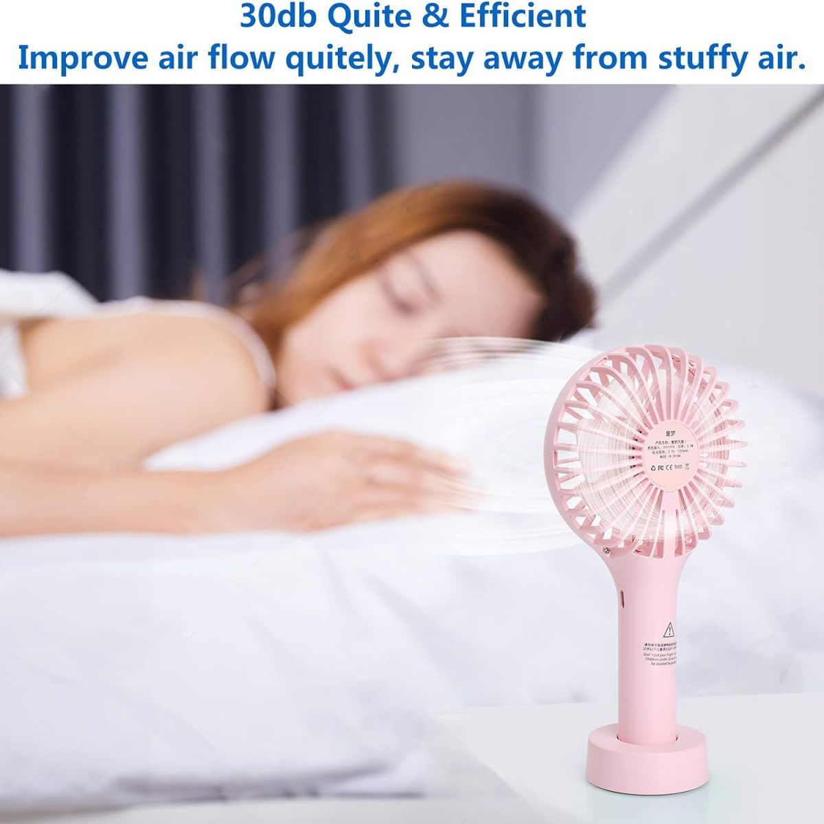 Ein rosa Handventilator steht neben einer schlafenden Person.