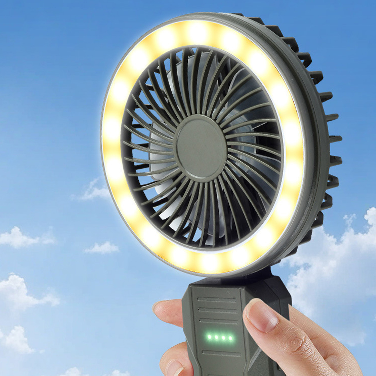 Eine Hand hält einen grauen Lüfter mit LED-Ring gegen blauen Himmel.