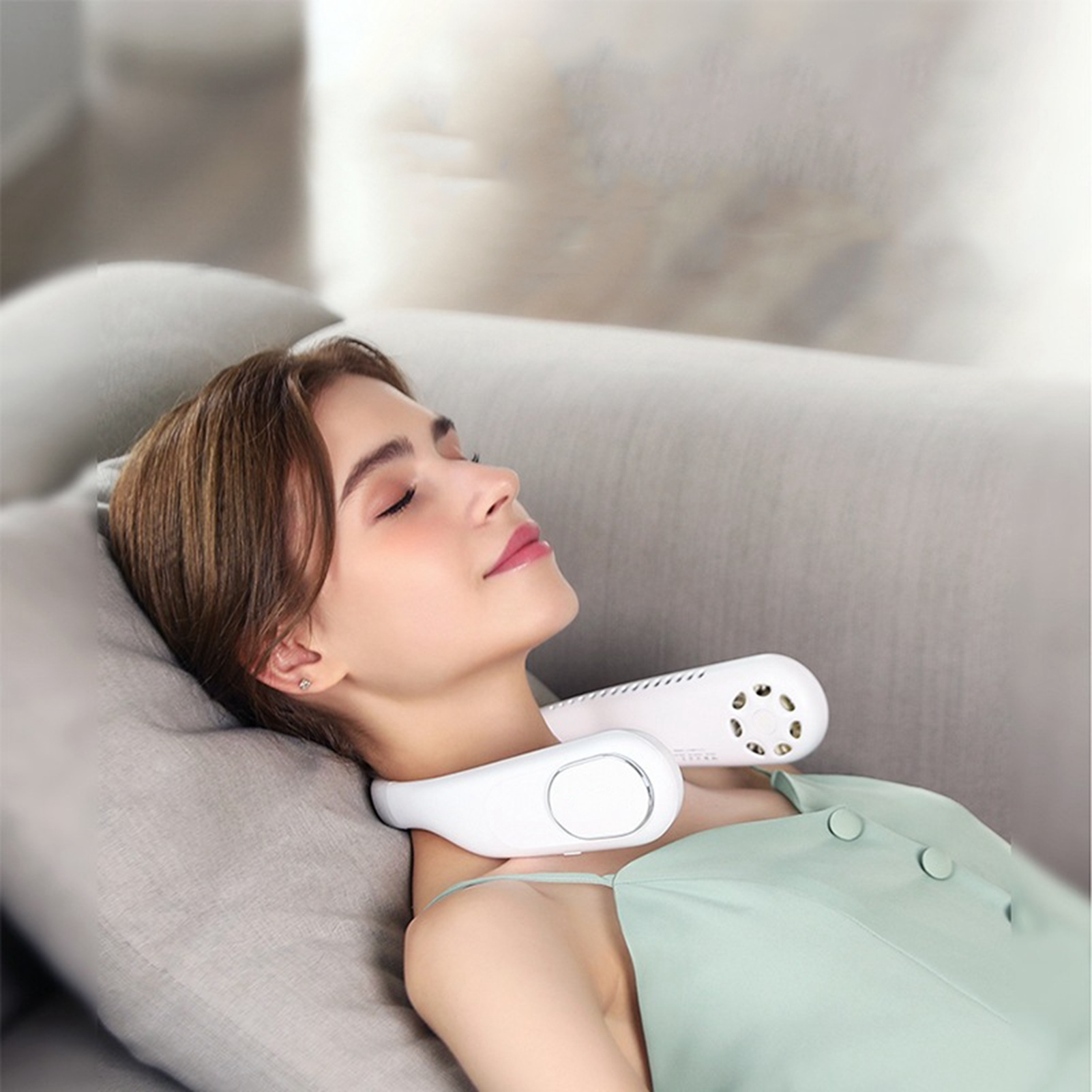 Frau mit Nackenventilator auf dem Sofa liegend, entspannt.