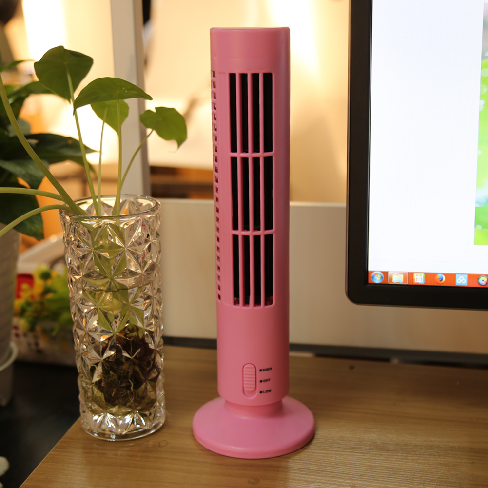 Ein kleiner rosa Ventilator steht neben einer Pflanze in einem Glas auf einem Schreibtisch.