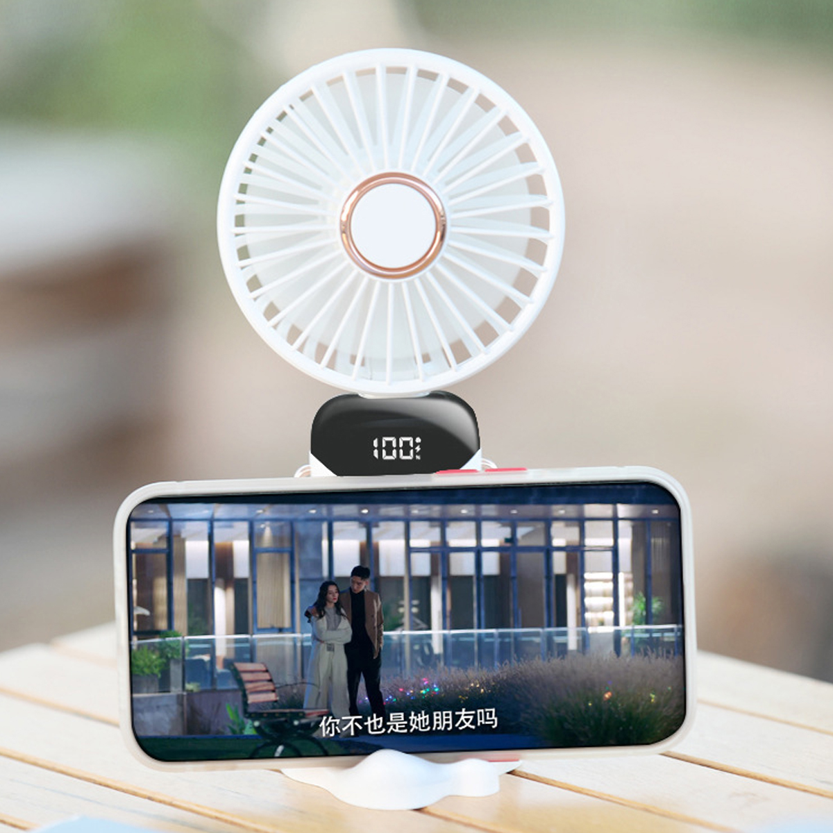 Ein weißer Ventilator mit digitaler Anzeige über einem Smartphone, das ein Paar zeigt.