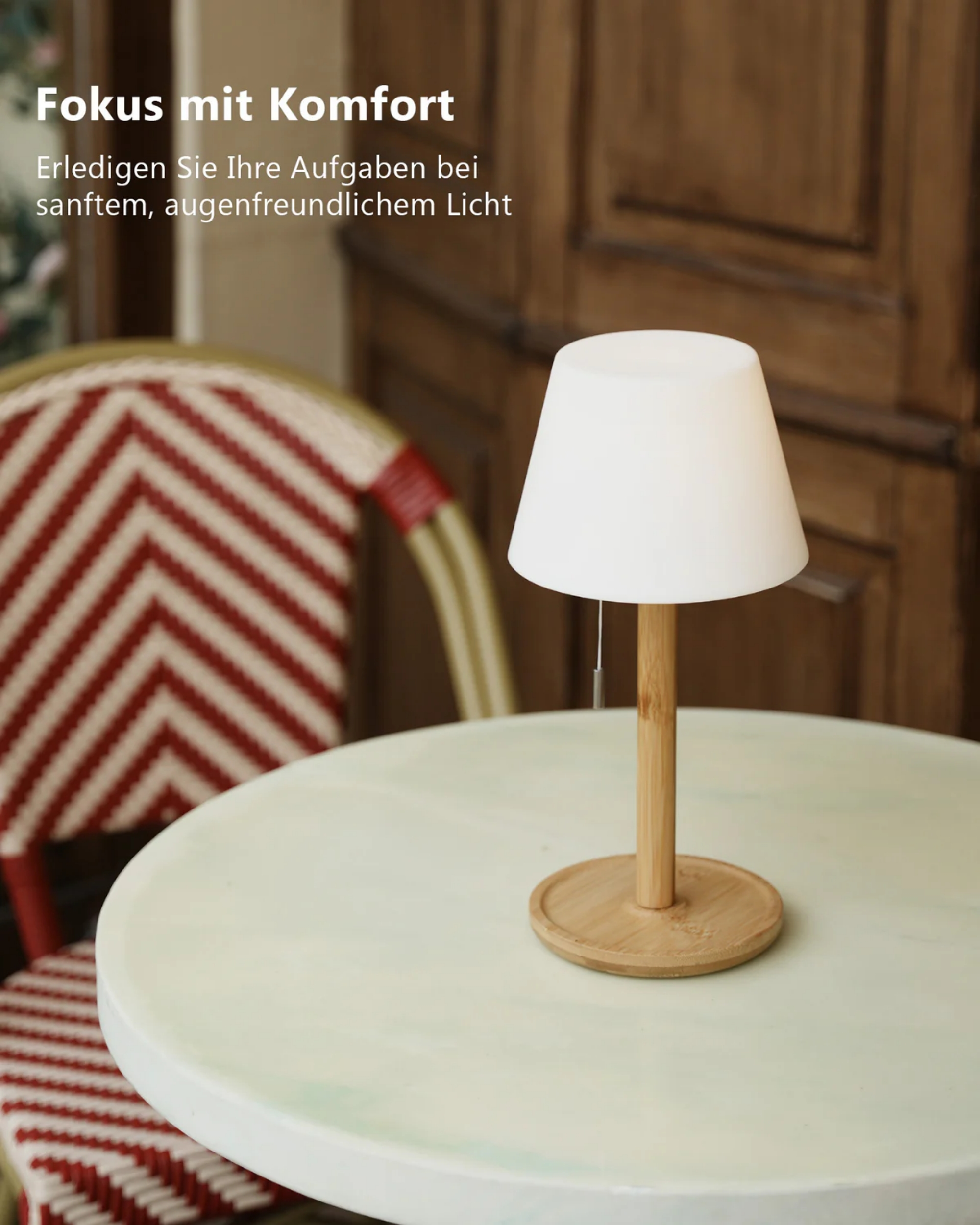 Eine weiße Lampe steht auf einem runden Tisch neben einem gestreiften Stuhl.