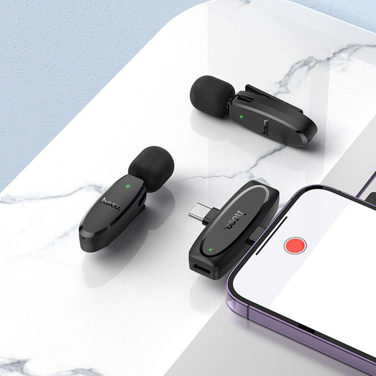 Tre microfoni neri con connettori USB-C su una superficie di marmo.