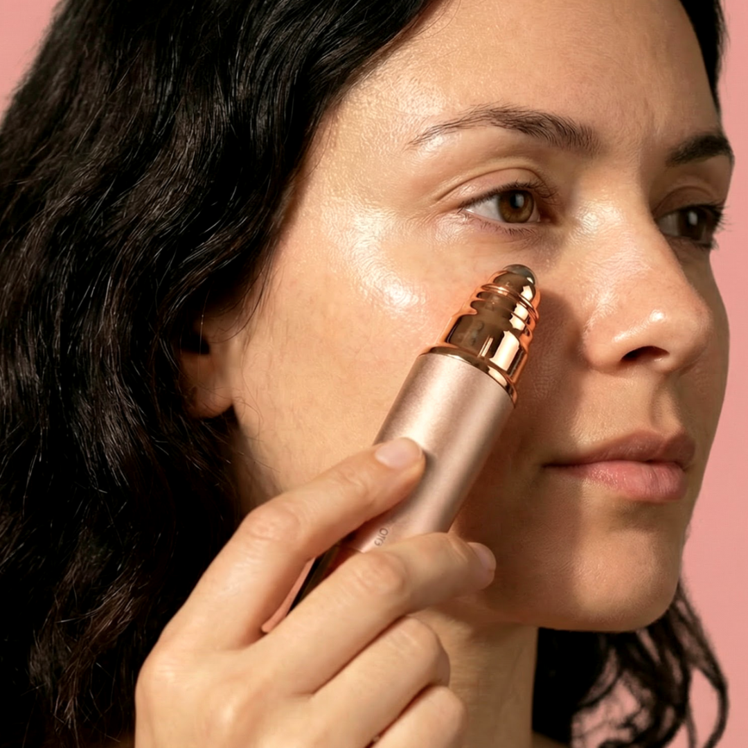 Kobieta używa różowo-złotego urządzenia do czyszczenia twarzy z obrotowymi włoskami.