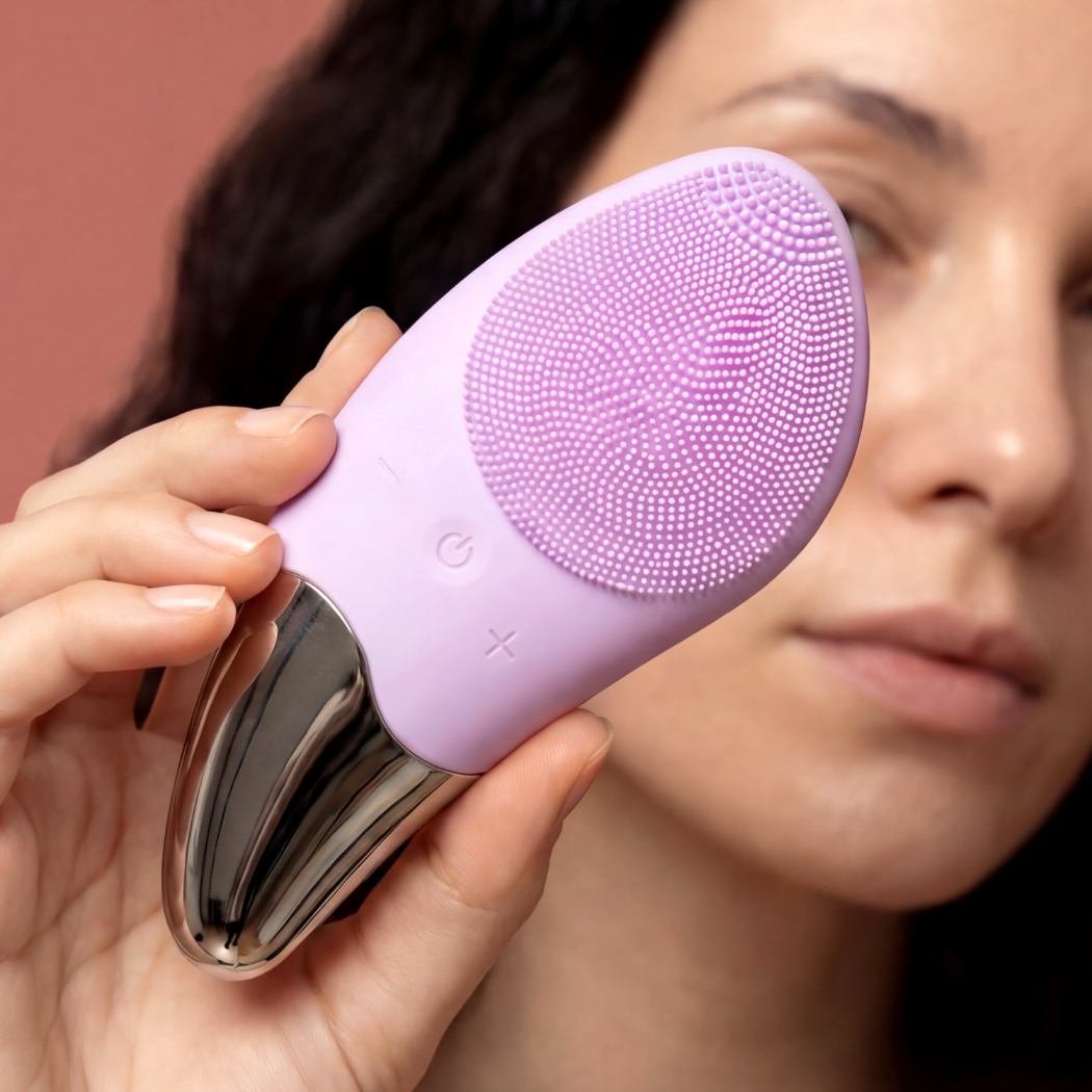 Osoba trzyma fioletowe urządzenie do oczyszczania twarzy ze srebrną końcówką.