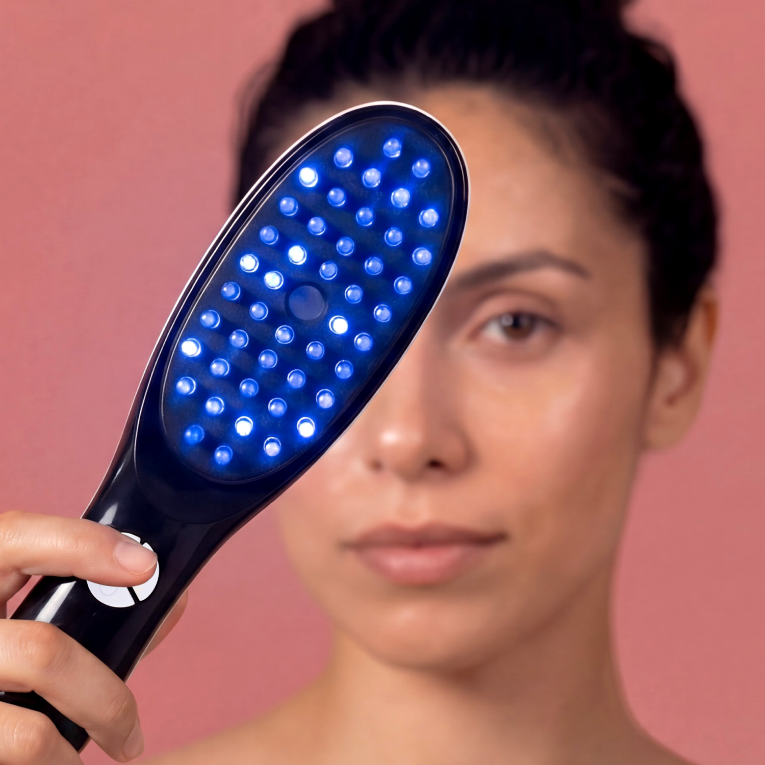 Primo piano di una donna che tiene un dispositivo a LED blu. Sfondo rosa.