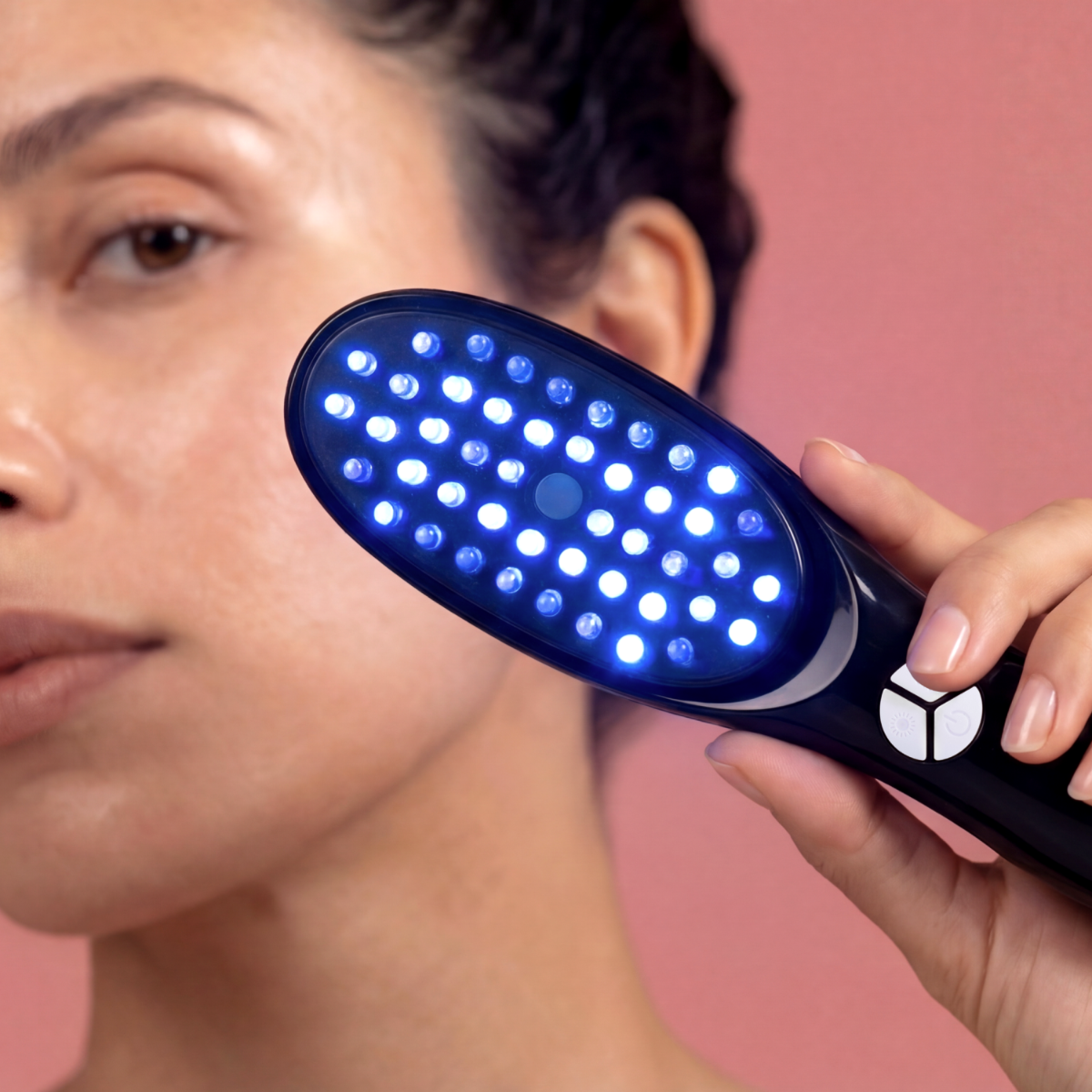 Una mano tiene un dispositivo nero con luci blu vicino al viso di una donna.