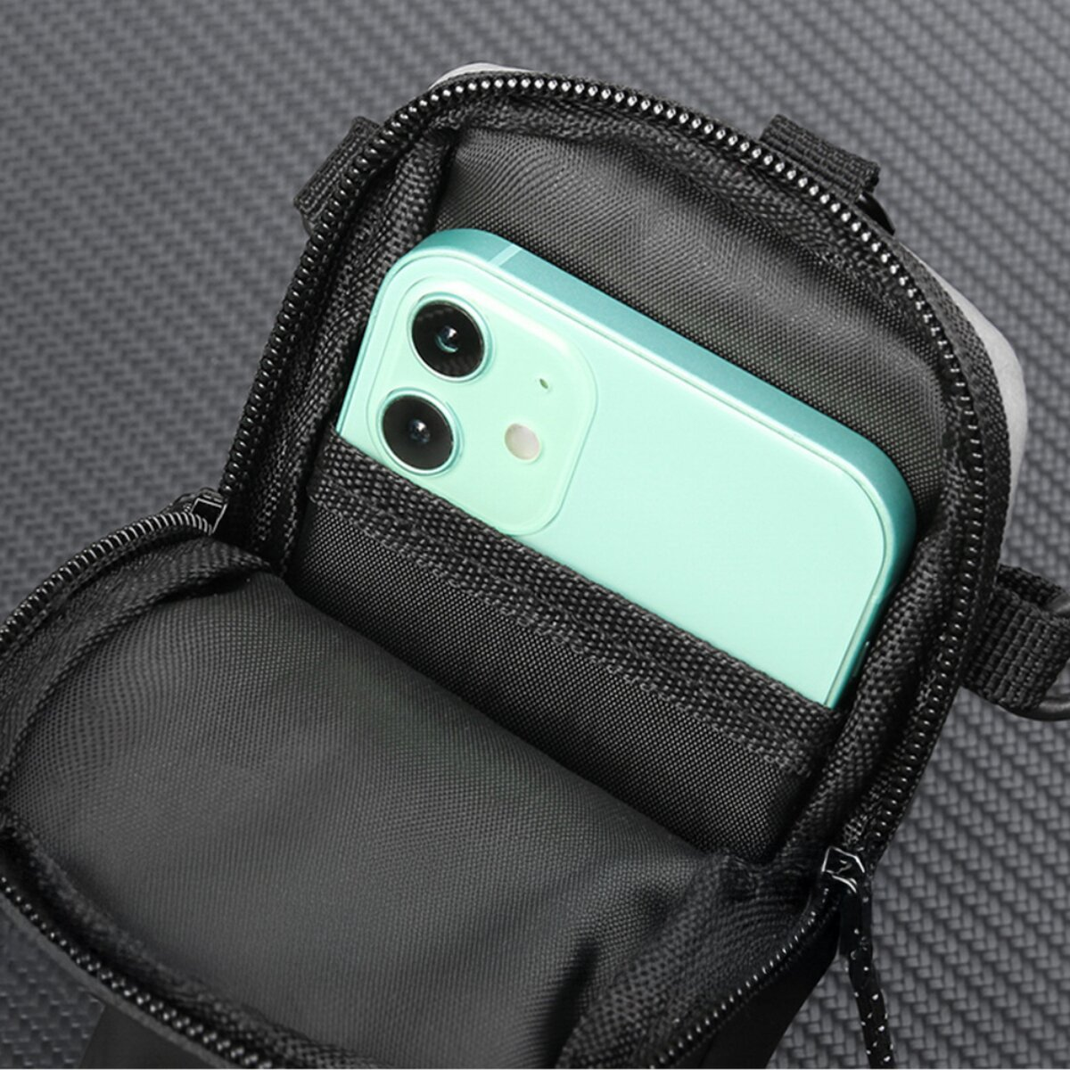 Ein hellgrünes Smartphone liegt in einer offenen schwarzen Tasche mit Reißverschluss.