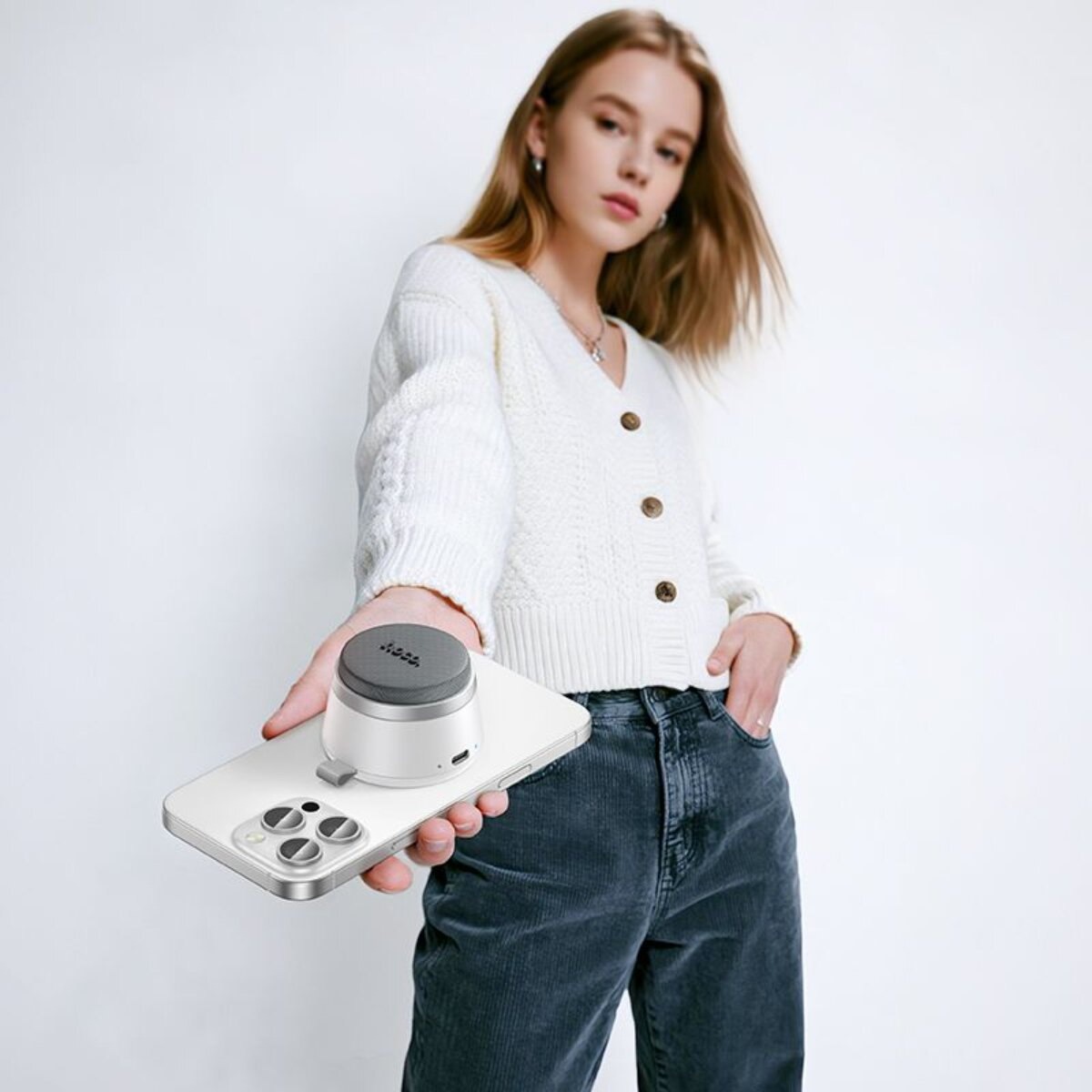 Eine Frau hält ein Smartphone mit einem kleinen Lautsprecher.