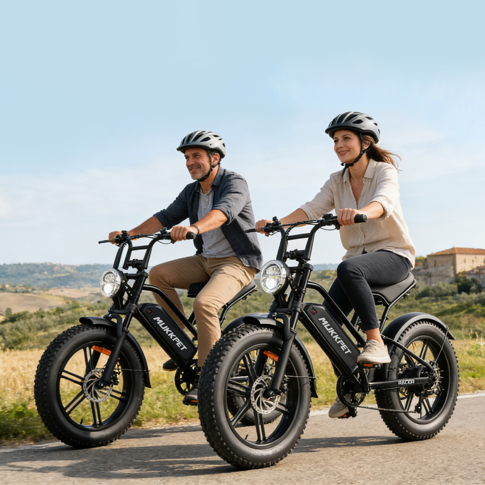 Ein Mann und eine Frau fahren E-Bikes auf einer Straße in ländlicher Gegend.