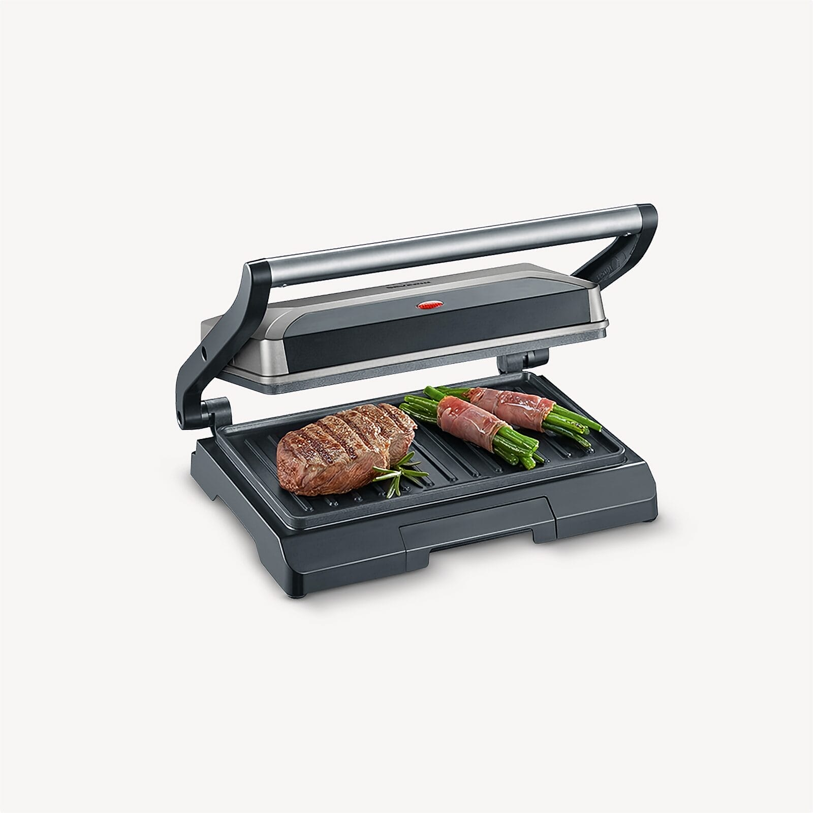 Een biefstuk en groene bonen in ham op een geopende contactgrill.