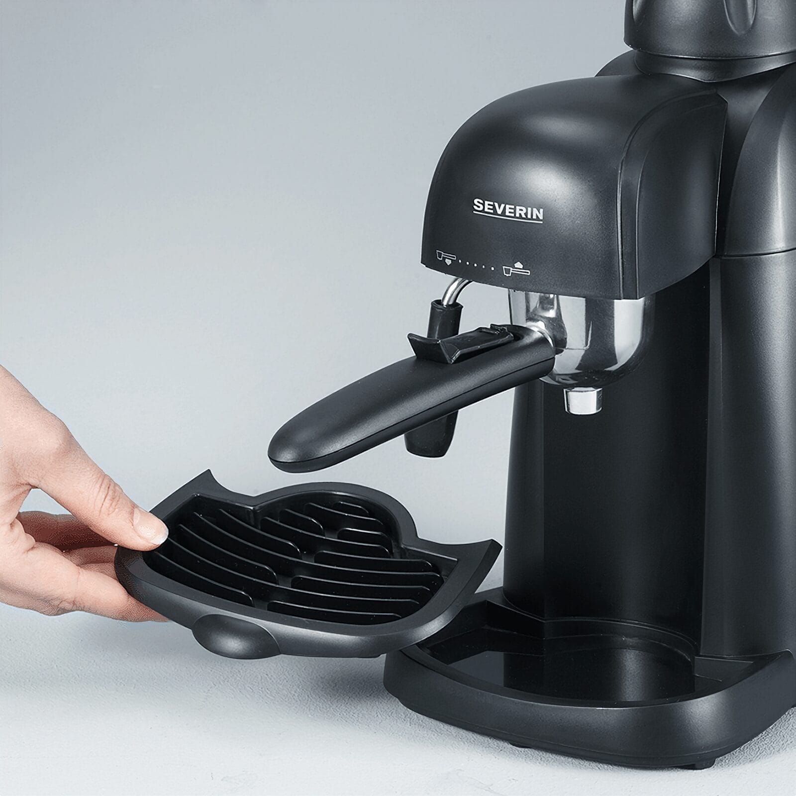 Eine Hand entfernt die Abtropfschale von einer schwarzen Severin-Kaffeemaschine.