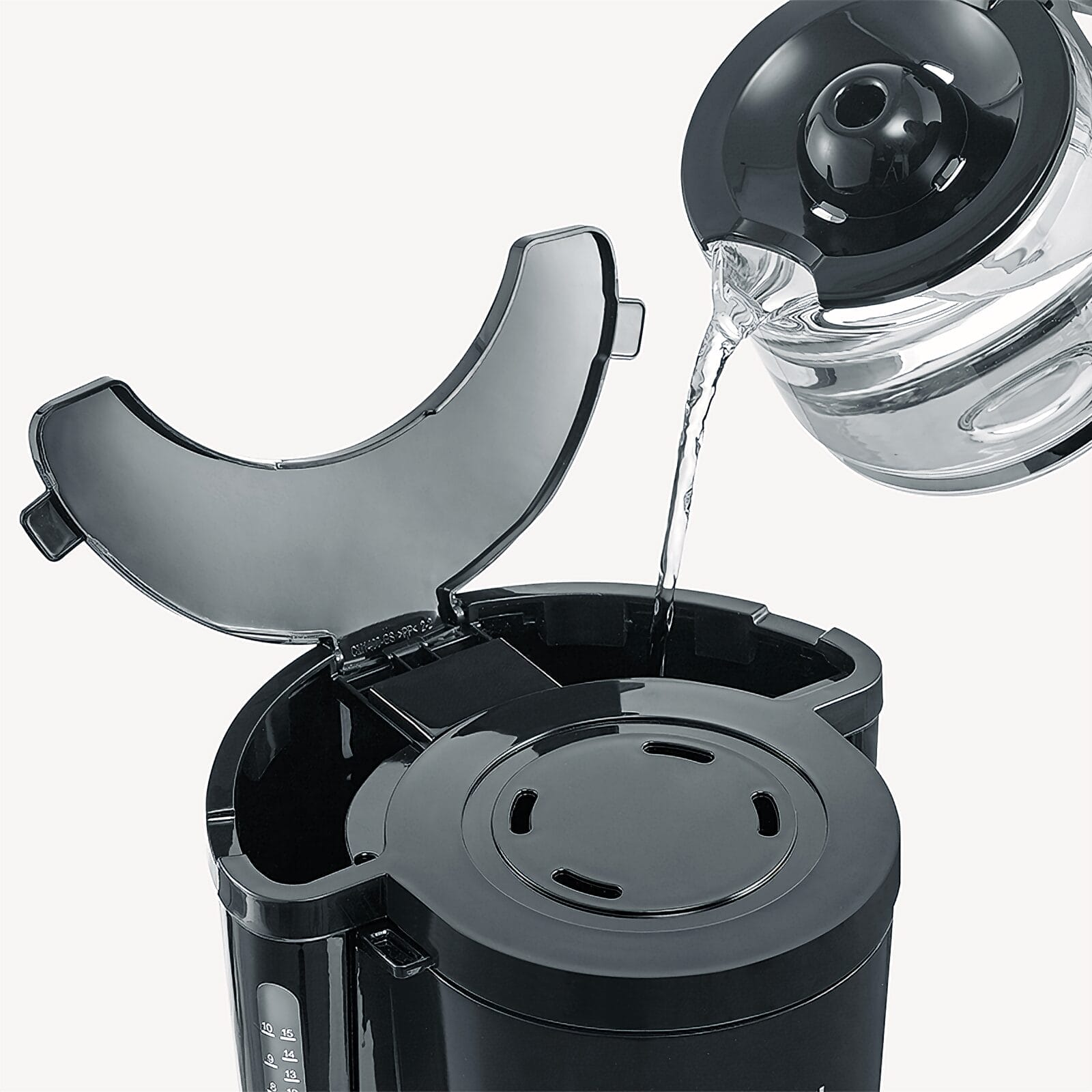 Woda jest nalewana z szklanego dzbanka do ekspresu do kawy.