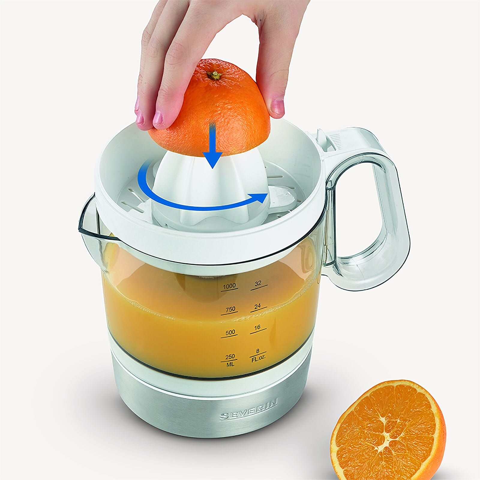 Eine Hand drückt eine Orange auf einen elektrischen Entsafter mit Saft darin.