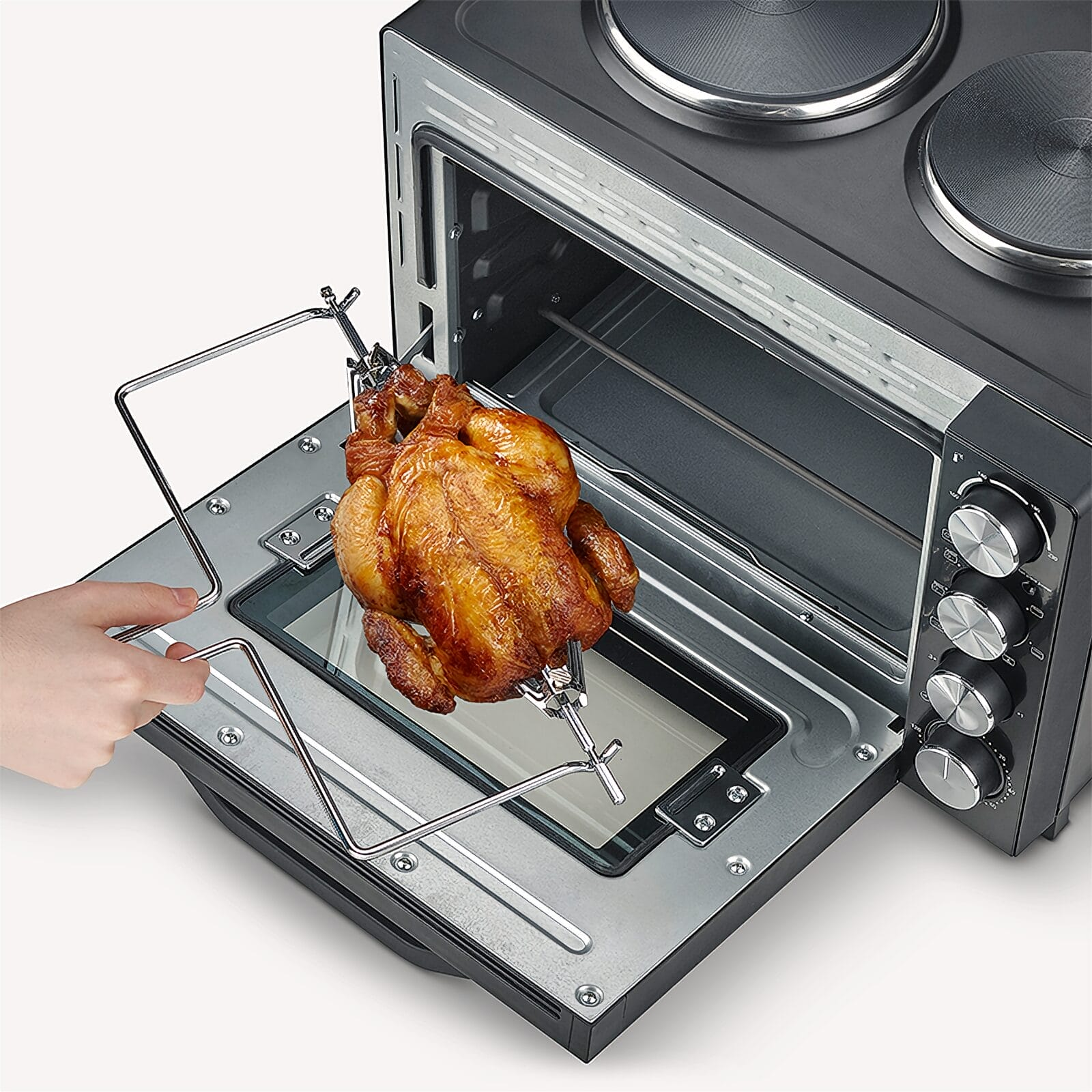 Un poulet rôti doré tourne sur une broche à l'intérieur d'un four ouvert.