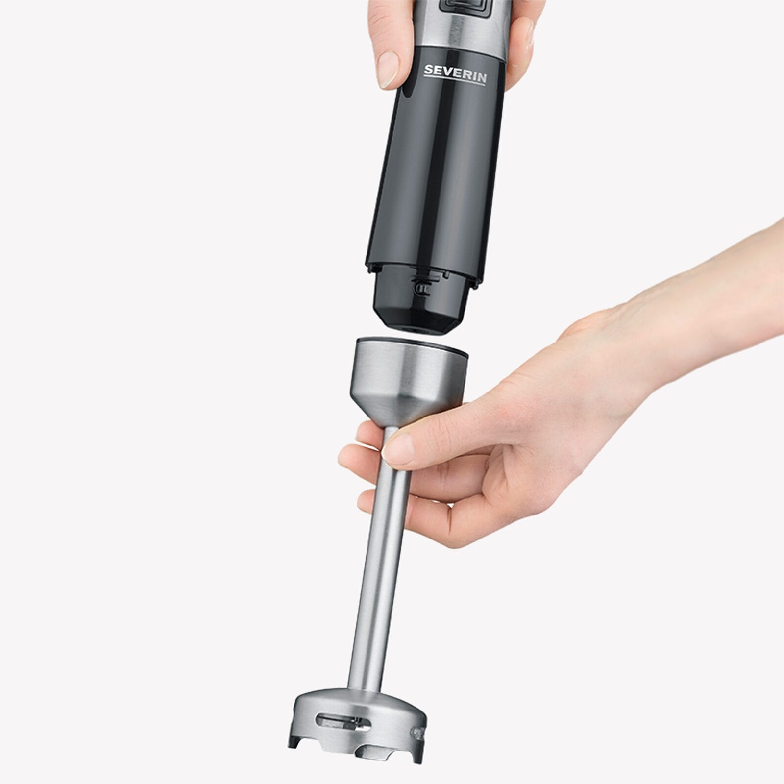 Een hand houdt een zwarte staafmixeropzetstuk vast, een andere hand houdt de mixer vast.