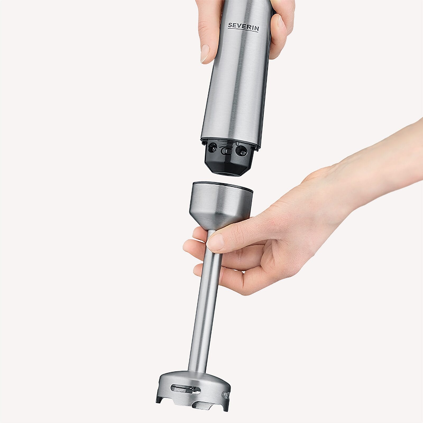 Hände montieren ein silbernes Stabmixer-Zubehörteil.