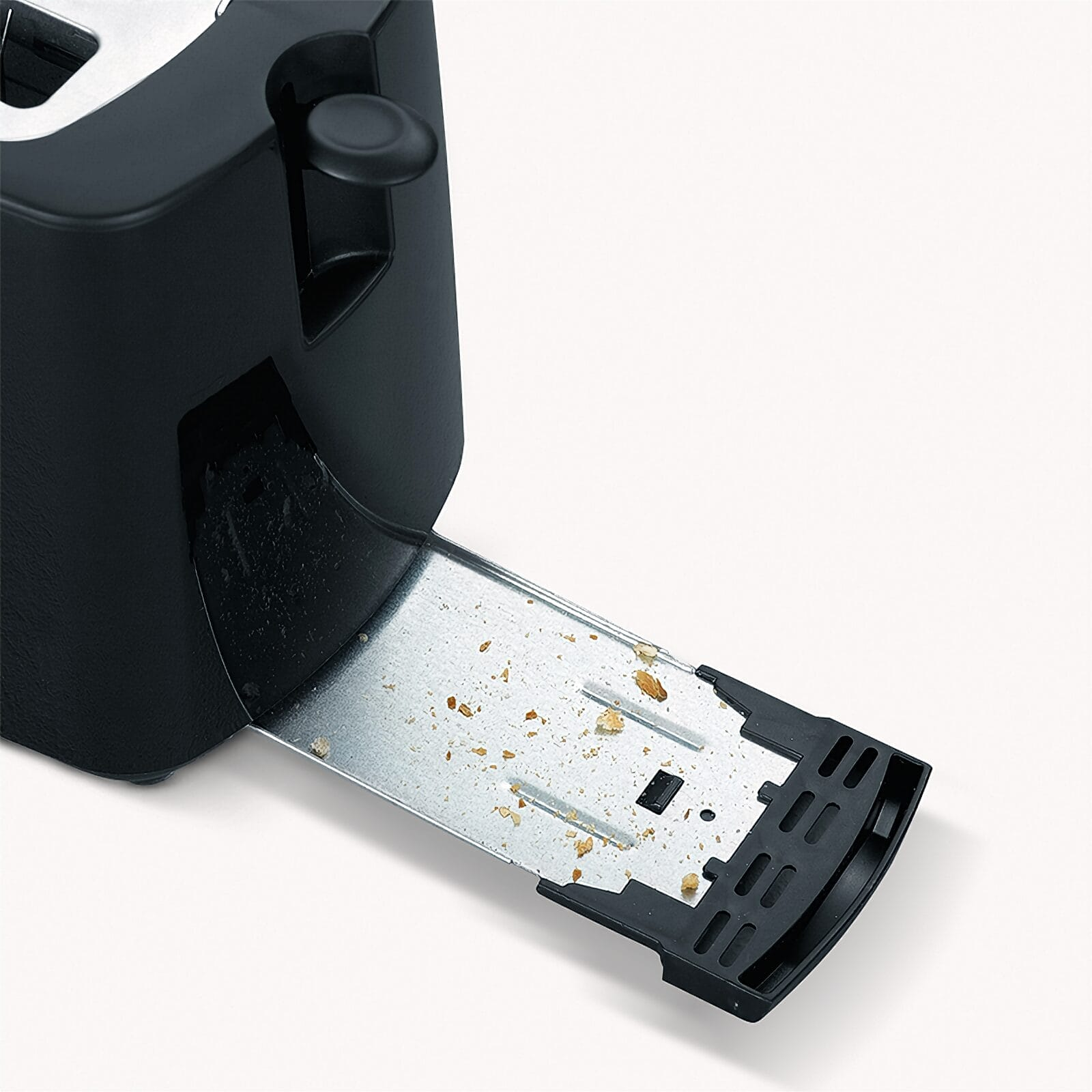 Czarny toster z wysuniętą tacką na okruchy, pokrytą okruchami.