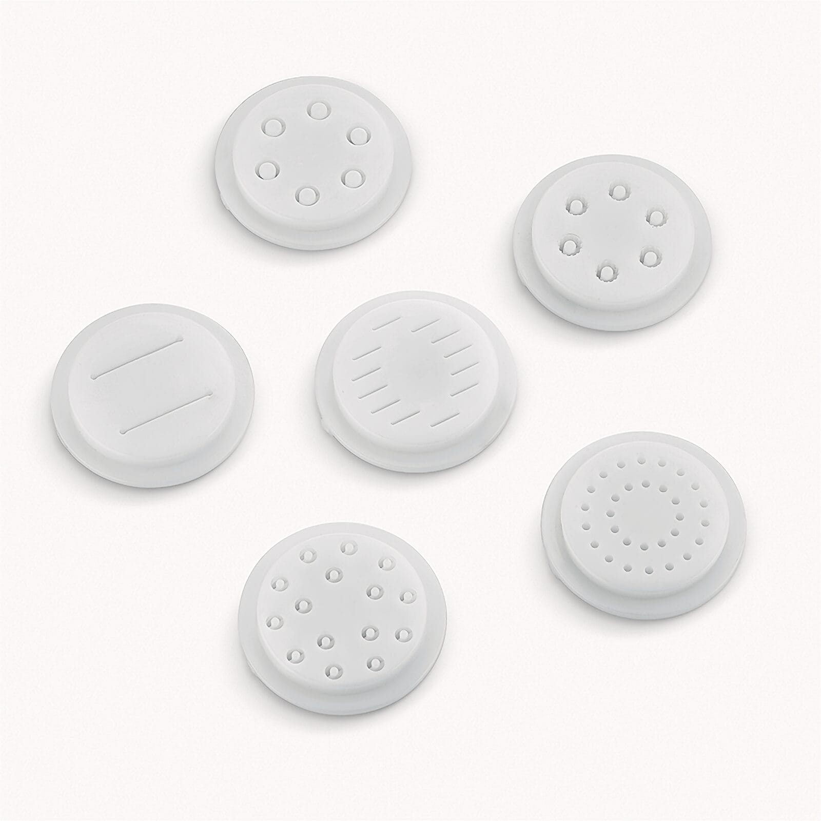 Sei accessori rotondi bianchi per pasta con vari motivi di fori su sfondo bianco.