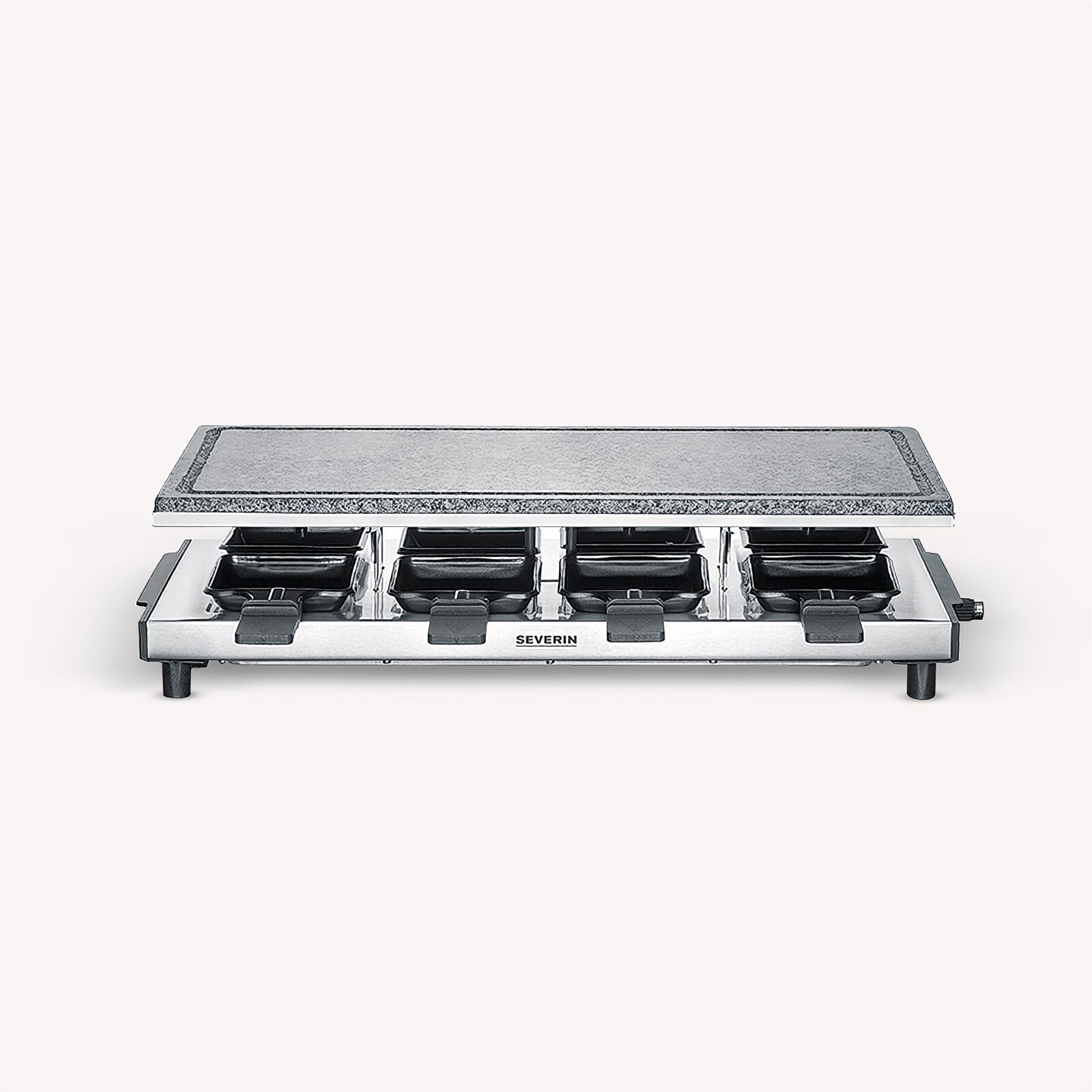 Stainless steel raclette grill with four pans and stone plate.